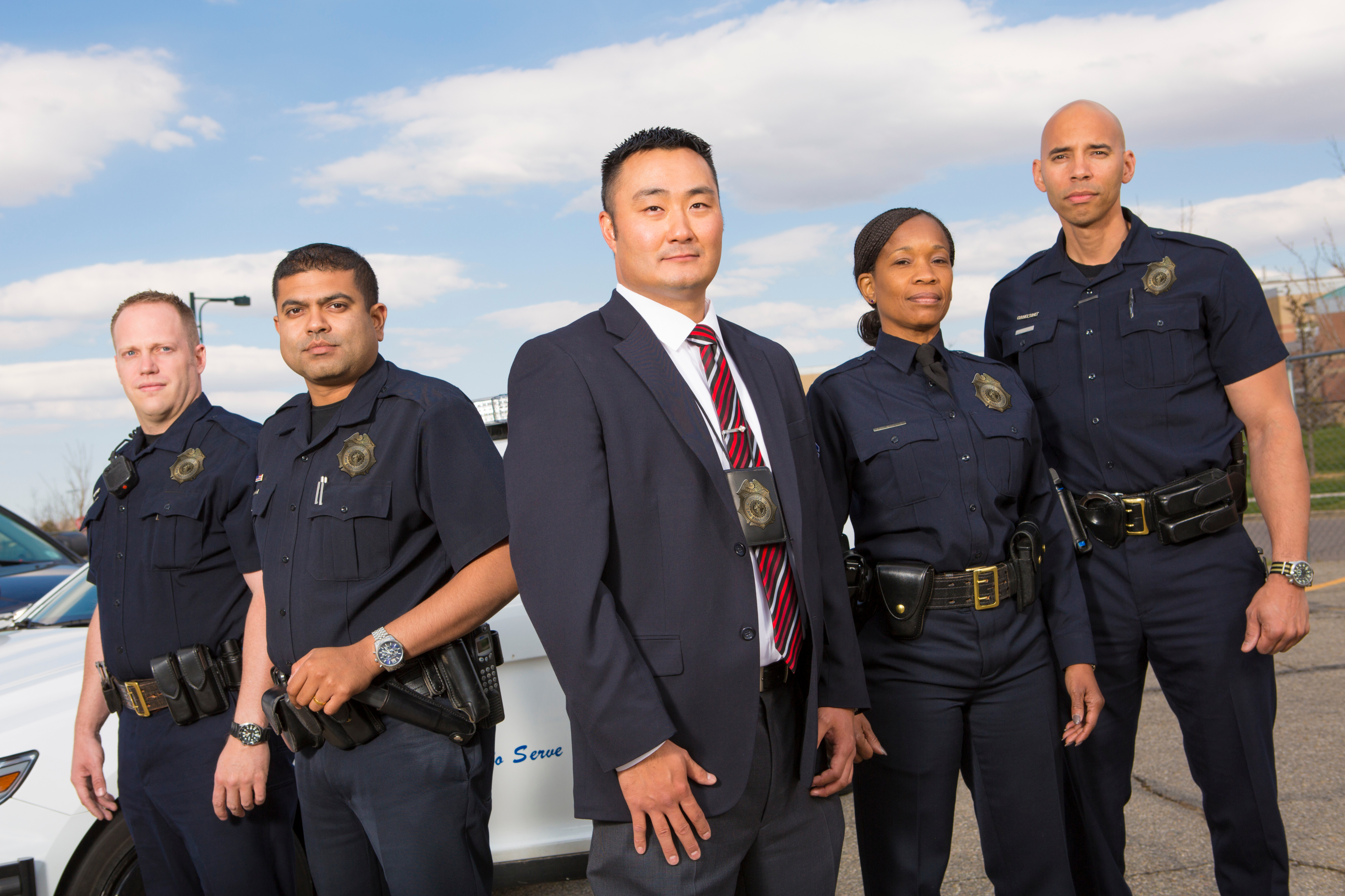 Five diverse enforcement officers stand together