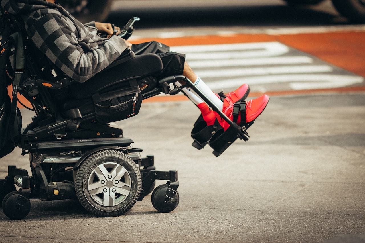 A person wearing red shoes operates a power wheelchair