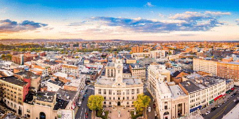 An aerial view of a city; includes city hall, streets, sidewalks, cars, and other government and non-government buildings