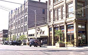 A photograph of a street scene in a downtown block. A street corner is shown with curb ramps.