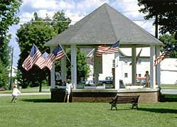 A photo of a gazebo in a public park surrounded by American flags.