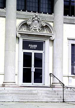 A photograph of the main entrance to a city police station. There are steps at the entrance and no ramp.