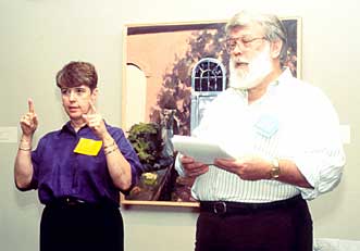 A photograph of a sign language interpreter signing for a speaker standing beside her.
